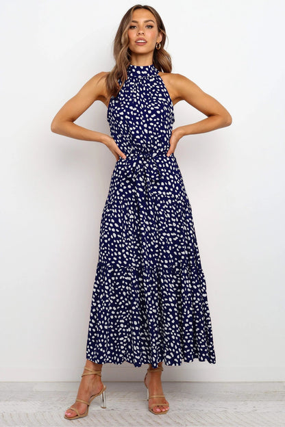 Donna in abito lungo blu a pois bianchi, senza maniche, con sandali dorati. Moda elegante, abbigliamento estivo, stile casual chic.