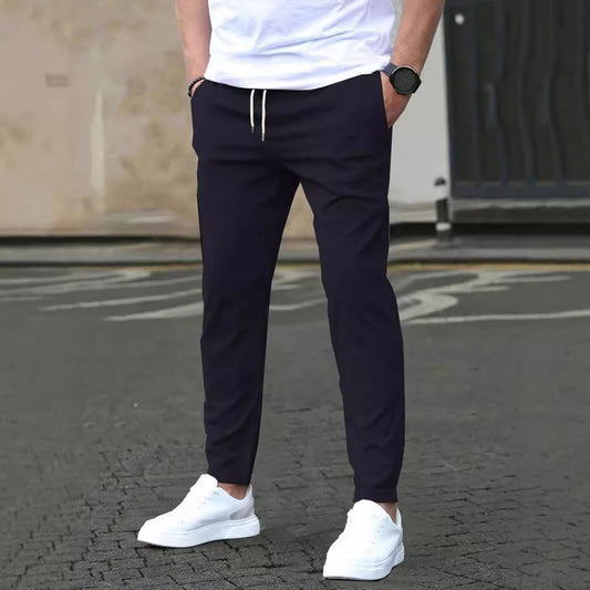 Uomo in pantaloni neri e scarpe bianche su strada asfaltata, moda casual maschile, abbigliamento urbano, stile moderno, orologio da polso.