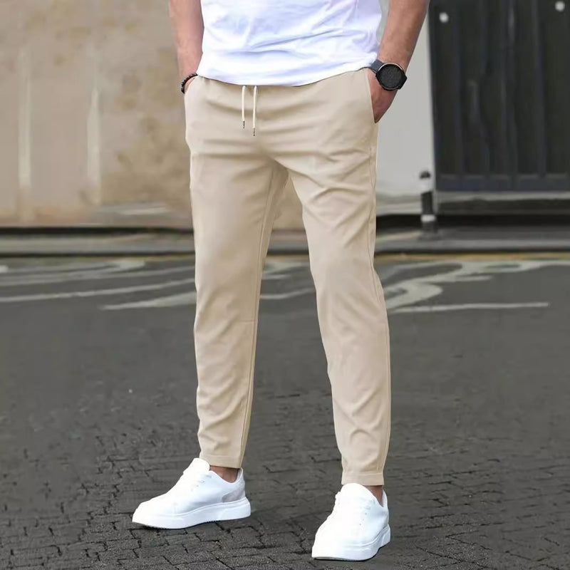 Pantaloni chino beige da uomo, abbinati a scarpe da ginnastica bianche e t-shirt bianca, moda casual maschile, stile urbano moderno.
