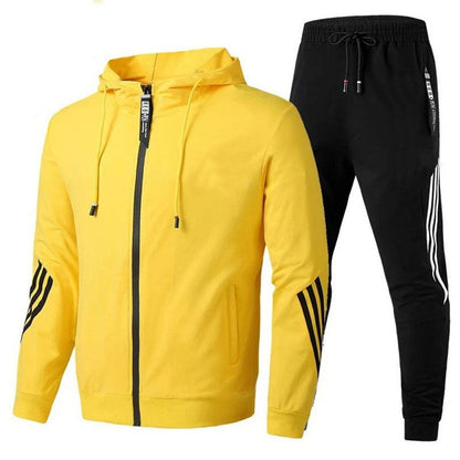 Tuta sportiva uomo: giacca gialla con cappuccio e pantaloni neri, dettagli a righe. Abbigliamento casual, moda fitness, stile moderno.