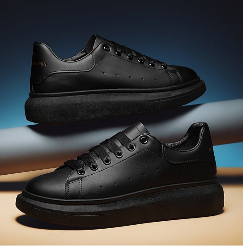 Scarpe da ginnastica nere eleganti su sfondo blu, design moderno e minimalista, suola spessa, perfette per moda urbana e casual.