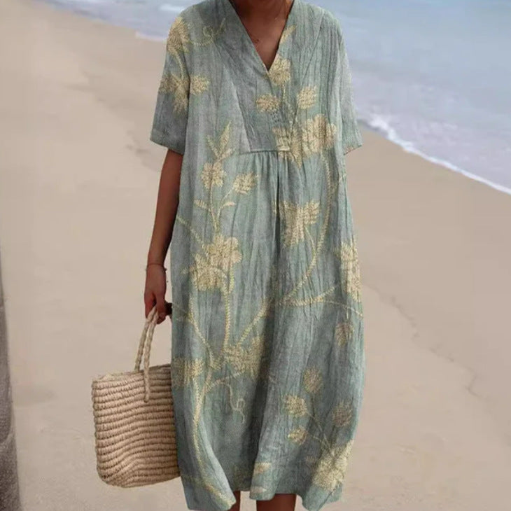 Donna in abito estivo floreale verde con borsa di paglia su spiaggia sabbiosa. Moda estiva, abbigliamento casual, stile vacanza mare.