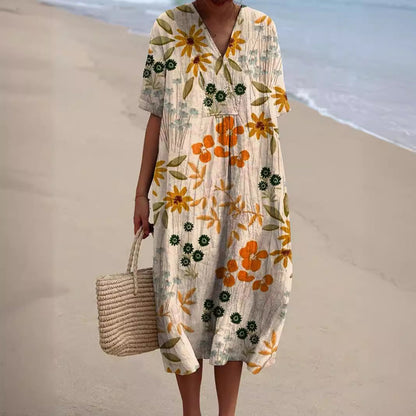 Abito estivo floreale donna, maniche corte, colori vivaci, spiaggia sullo sfondo. Moda mare, abbigliamento casual, stile boho chic.