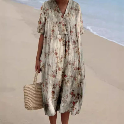 Abito estivo floreale lungo, stile boho, indossato su spiaggia sabbiosa. Vestito casual con borsa di paglia, moda mare donna.
