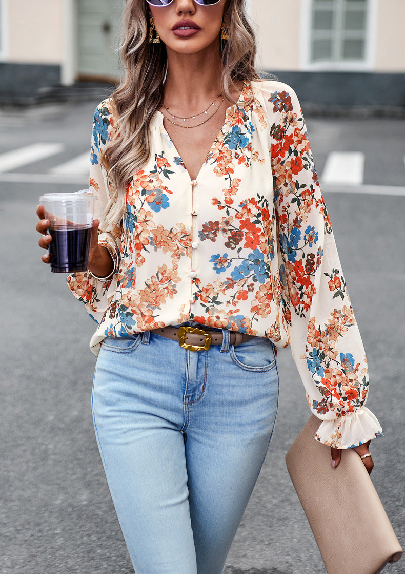 Donna con camicia floreale colorata, jeans chiari, occhiali da sole e bevanda in mano. Moda casual estiva, stile urbano elegante.