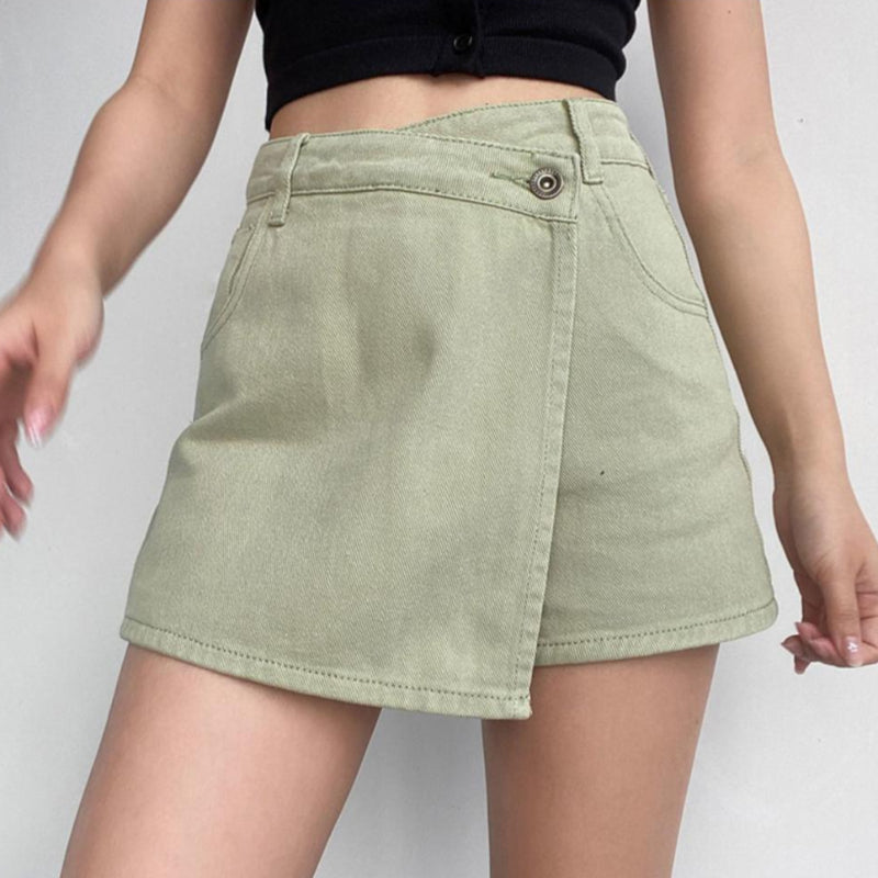 Minigonna verde chiaro in denim con design asimmetrico, indossata da una donna con top nero. Moda estiva casual, abbigliamento femminile trendy.