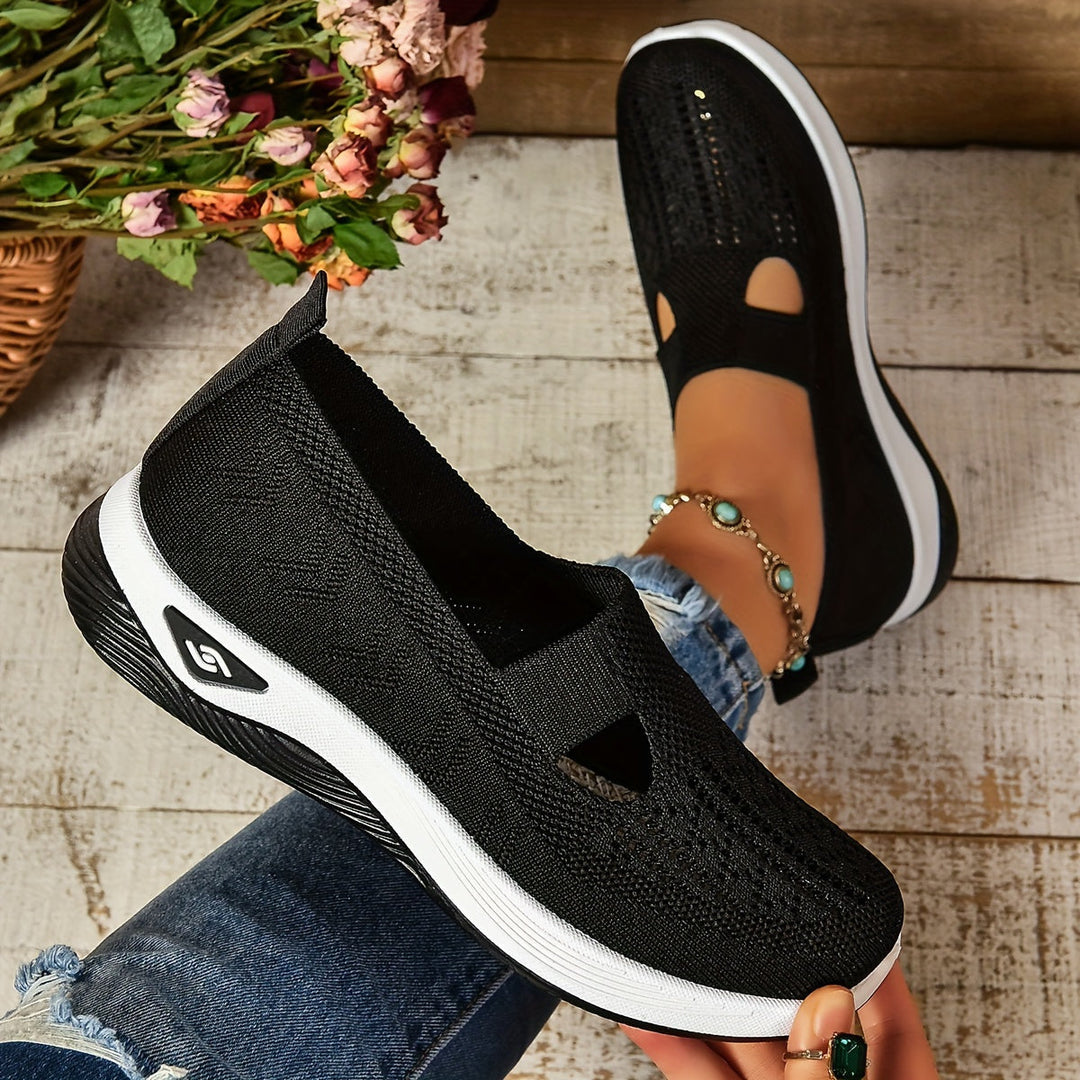 Scarpe da donna nere in tessuto traspirante, suola bianca, indossate con jeans. Design casual e moderno, ideali per passeggiate e tempo libero.