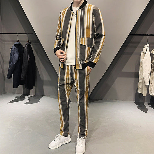 Completo uomo a righe verticali gialle e grigie, giacca e pantaloni abbinati, indossato con scarpe bianche, in negozio di moda moderna.
