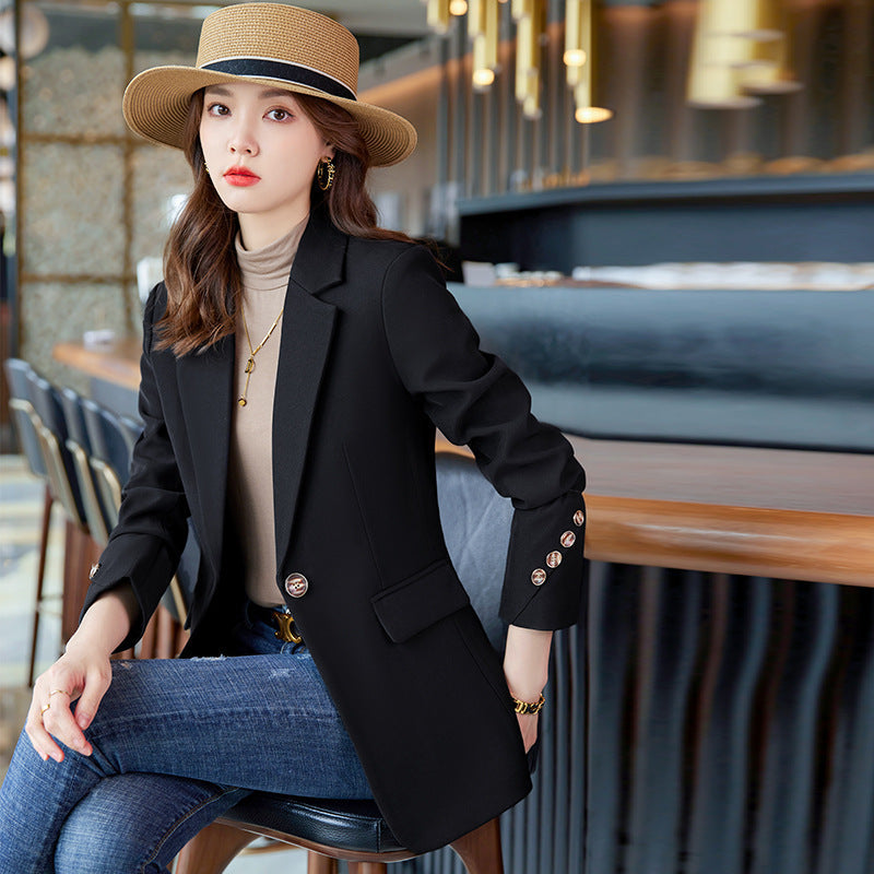 Donna elegante con cappello di paglia, blazer nero e jeans seduta in un caffè moderno. Moda autunnale, stile casual chic, abbigliamento femminile.