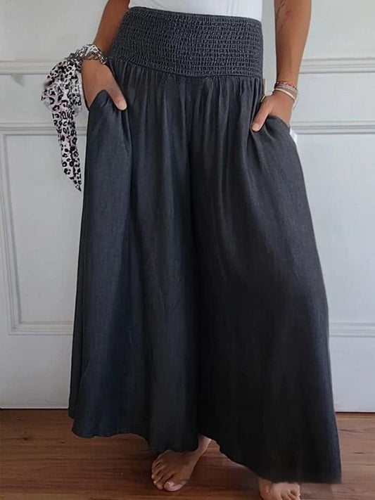 Gonna lunga nera a vita alta con tasche, indossata da una persona a piedi nudi. Stile casual, tessuto morbido, perfetta per look estivi.