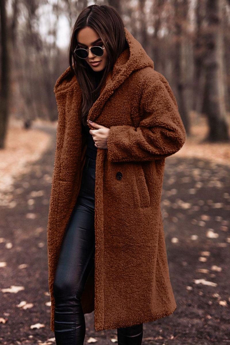 Donna con cappotto teddy marrone, occhiali da sole, pantaloni in pelle nera, passeggia in un parco autunnale. Moda autunno inverno, stile casual chic.
