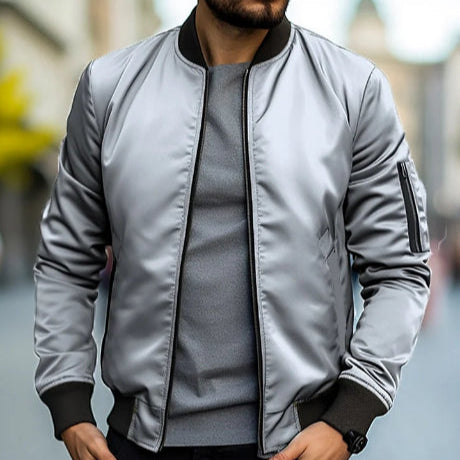 Giacca bomber grigia da uomo, stile casual, indossata su maglietta grigia. Moda urbana, abbigliamento autunnale, tendenza streetwear maschile.