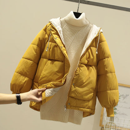 Giacca invernale gialla imbottita con cappuccio, abbinata a maglione a collo alto color crema. Moda autunnale, abbigliamento caldo e casual.