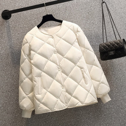 Giacca trapuntata bianca appesa su gruccia, design elegante e moderno, perfetta per l'inverno. Sfondo grigio, borsa nera a catena visibile.