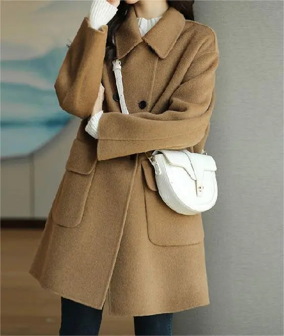 Cappotto marrone elegante donna, doppio petto, tasche grandi, abbinato a borsa bianca a tracolla. Moda autunnale, stile casual chic.