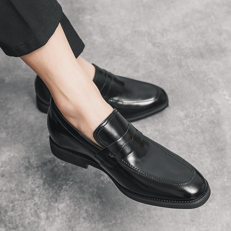 Scarpe eleganti nere in pelle lucida indossate, su pavimento grigio. Mocassini da uomo, moda formale, calzature di lusso, stile classico.