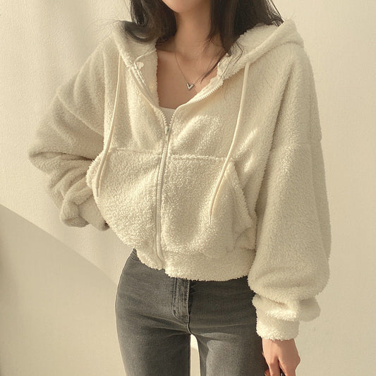 Donna con felpa bianca in pile, cappuccio e zip, indossa jeans grigi. Moda casual autunnale, abbigliamento comodo e caldo.
