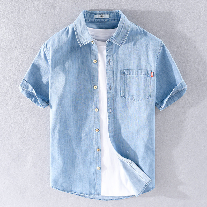Camicia di jeans azzurra a maniche corte con taschino, abbinata a t-shirt bianca. Moda casual estiva, abbigliamento uomo trendy.