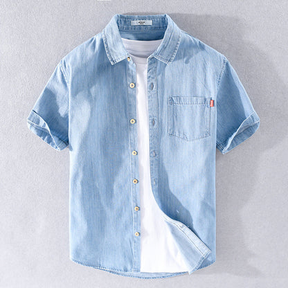 Camicia di jeans azzurra a maniche corte con taschino, abbinata a t-shirt bianca. Moda casual estiva, abbigliamento uomo trendy.