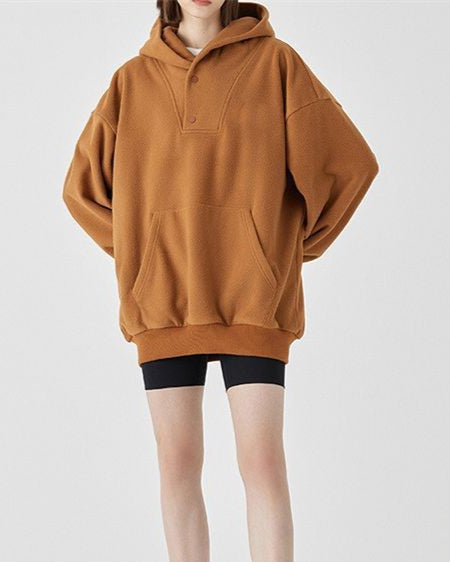 Donna con felpa oversize marrone e pantaloncini neri. Moda casual autunnale, abbigliamento comodo, stile urbano.
