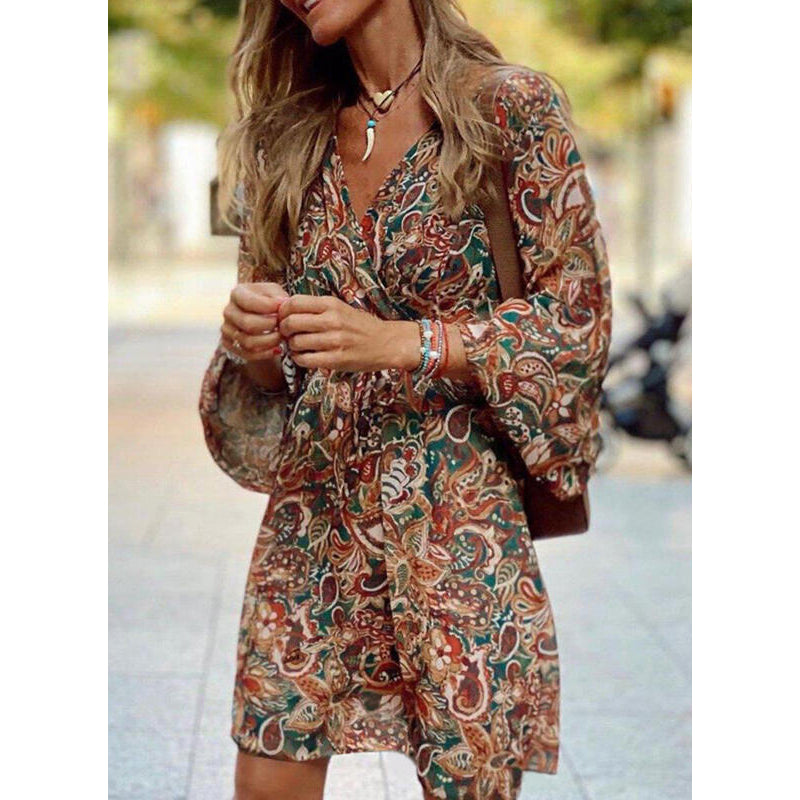 Donna con abito boho a fantasia floreale, maniche lunghe, in strada. Moda autunnale, stile casual chic, accessori eleganti.