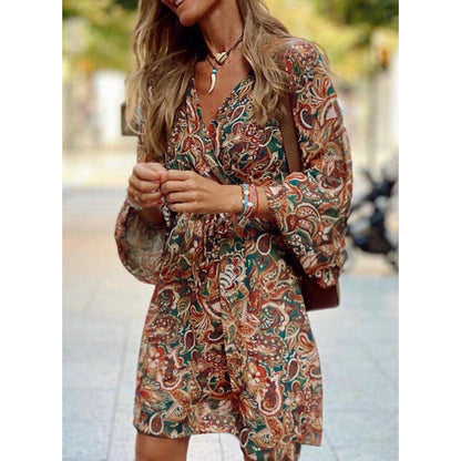 Donna con abito boho a fantasia floreale, maniche lunghe, in strada. Moda autunnale, stile casual chic, accessori eleganti.
