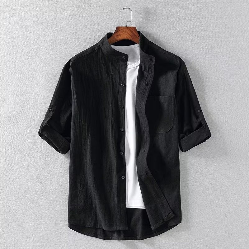 Camicia nera casual da uomo con colletto alla coreana, maniche lunghe arrotolate, abbinata a t-shirt bianca. Stile moderno ed elegante.