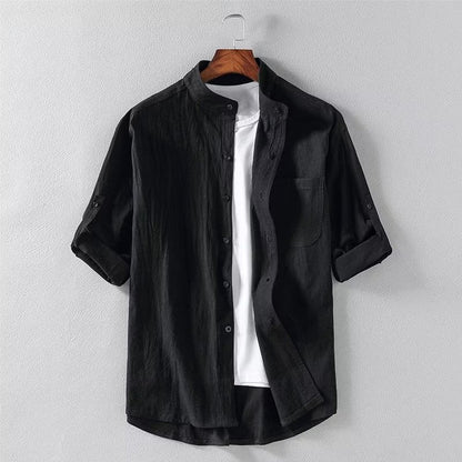 Camicia nera casual da uomo con colletto alla coreana, maniche lunghe arrotolate, abbinata a t-shirt bianca. Stile moderno ed elegante.