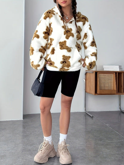 Donna con maglione in pile bianco con orsacchiotti marroni, pantaloncini neri, borsa a tracolla nera e scarpe beige. Stile casual autunnale.