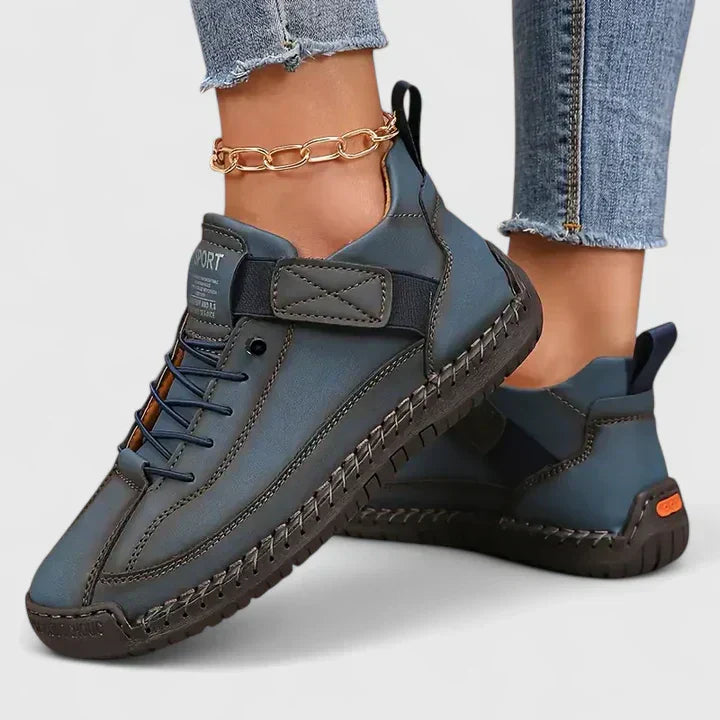 Scarpe sportive blu scuro da donna, design moderno con suola antiscivolo, chiusura a strappo, indossate con jeans strappati e cavigliera dorata.