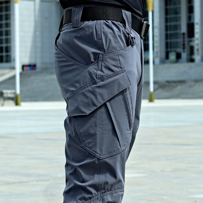 Pantaloni cargo grigi da uomo con tasche multiple, indossati all'aperto. Stile casual, tessuto resistente, ideale per attività all'aperto.