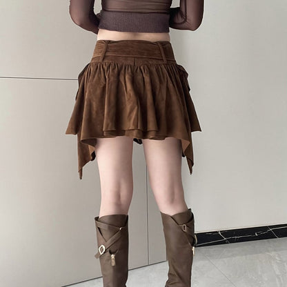 Donna con gonna marrone asimmetrica in pelle scamosciata e stivali alti marroni. Moda autunnale, abbigliamento casual elegante.