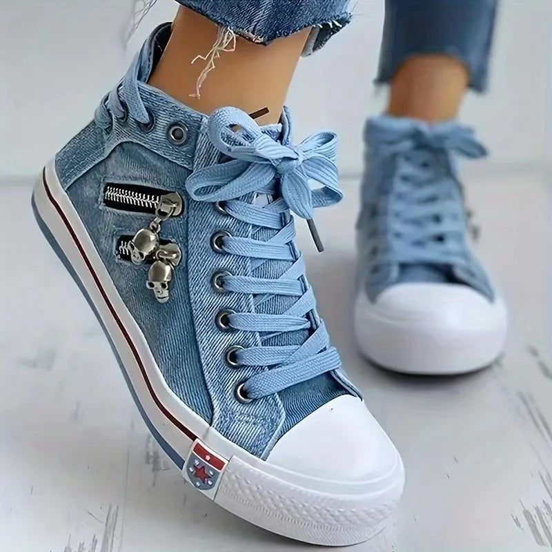Scarpe da ginnastica alte in denim blu con cerniera e decorazione a teschio, suola bianca, lacci azzurri, moda casual, stile urbano.