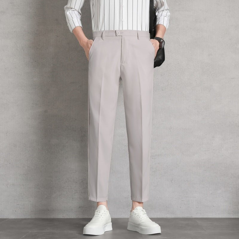 Uomo in camicia a righe e pantaloni beige, mani in tasca, indossa scarpe bianche. Moda maschile elegante, abbigliamento casual chic.