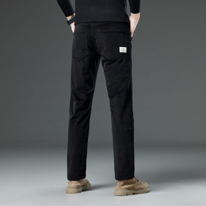 Jeans neri da uomo, vestibilità slim, con etichetta sul retro, indossati con scarpe marroni su sfondo grigio. Moda maschile casual.
