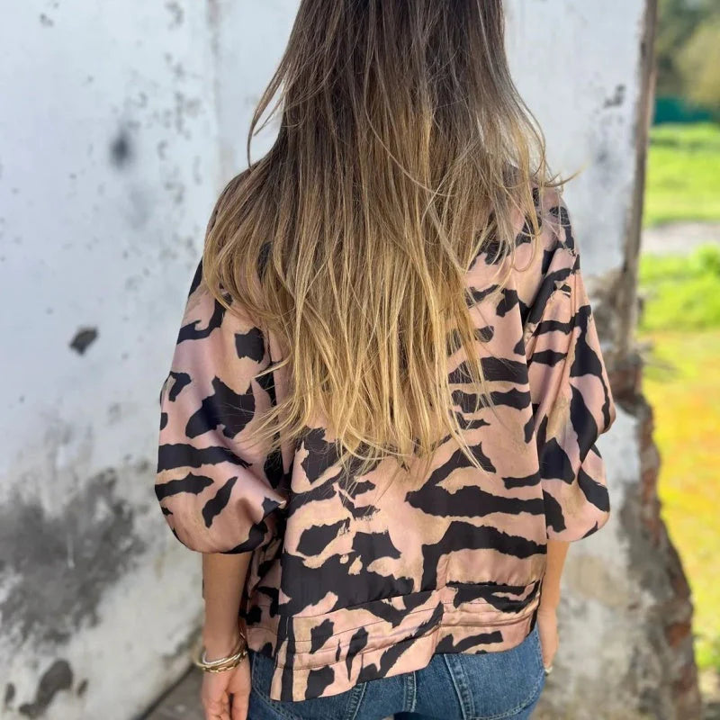 Donna con giacca a stampa animalier e capelli lunghi biondi, di spalle, all'aperto. Moda femminile, stile casual, tendenze abbigliamento.