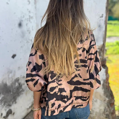 Donna con giacca a stampa animalier e capelli lunghi biondi, di spalle, all'aperto. Moda femminile, stile casual, tendenze abbigliamento.