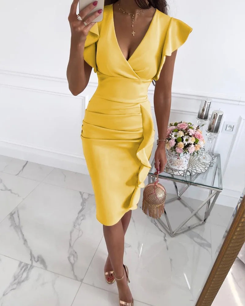 Donna in abito giallo elegante con volant, scatta selfie in specchio. Tavolino con fiori e borsa decorata. Moda estiva, stile chic.
