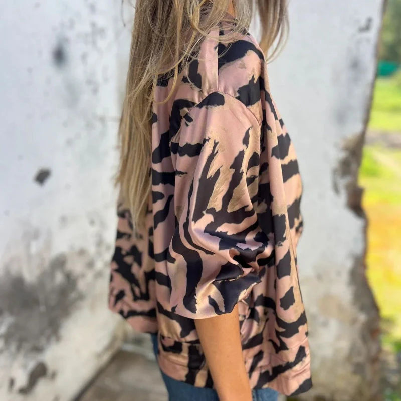 Giacca a fantasia animalier, motivo leopardato nero su sfondo beige, indossata da una donna con capelli lunghi. Moda autunnale, stile casual.