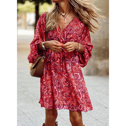 Donna con abito rosso a fantasia floreale, maniche lunghe, collana e borsa marrone. Moda estiva, look casual chic, tendenze abbigliamento femminile.