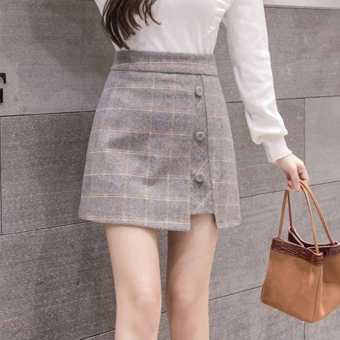 Gonna a quadri grigia con bottoni, abbinata a maglia bianca a maniche lunghe. Moda femminile autunnale, stile casual elegante.