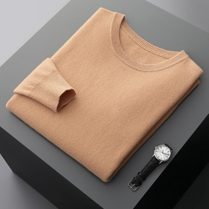 Maglione beige piegato su tavolo grigio con orologio da polso nero e quadrante bianco. Moda uomo, abbigliamento elegante, accessori di lusso.