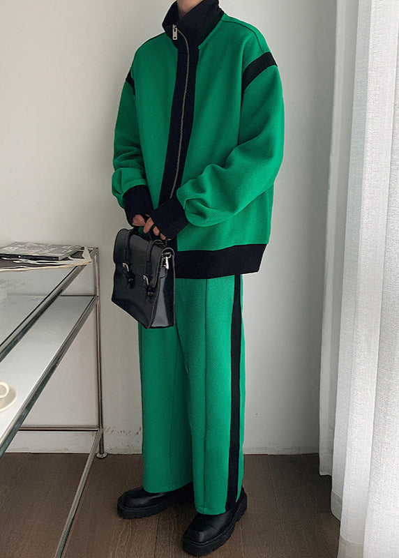 Tuta sportiva verde con dettagli neri, giacca con zip e pantaloni abbinati, borsa a tracolla nera, scarpe nere, stile casual moderno.