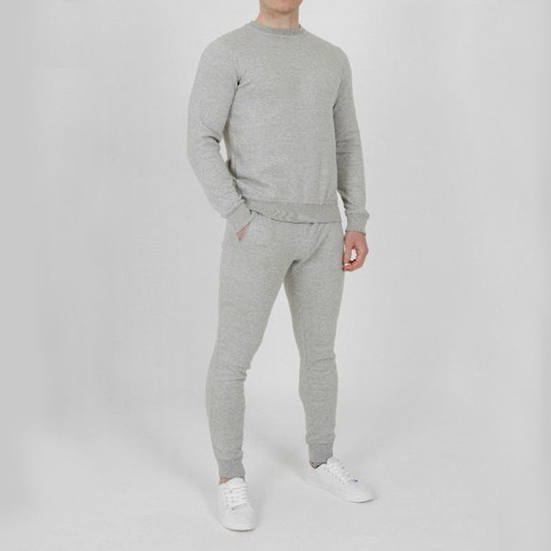 Uomo in tuta grigia, composta da felpa e pantaloni, su sfondo bianco. Abbigliamento casual, moda uomo, stile comodo.