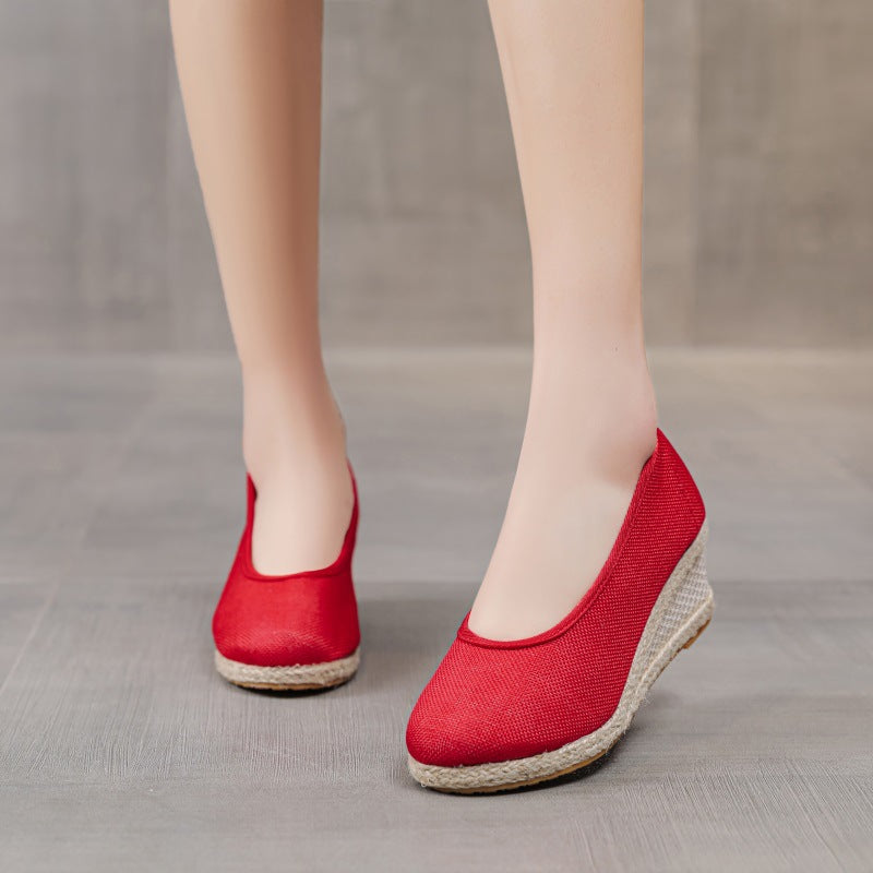 Scarpe con zeppa rosse in tessuto, design elegante e moderno, perfette per l'estate. Scarpe da donna comode e alla moda su pavimento grigio.
