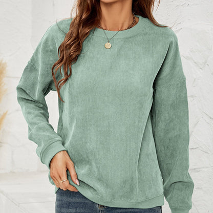 Donna con maglione verde menta in velluto a coste, collana dorata e jeans. Moda casual autunnale, abbigliamento femminile trendy.
