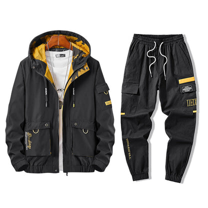 Completo sportivo uomo nero con dettagli gialli, giacca con cappuccio e pantaloni con tasche multiple. Moda streetwear, abbigliamento casual.