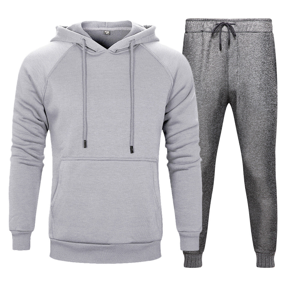 Tuta sportiva grigia da uomo, composta da felpa con cappuccio e pantaloni, ideale per allenamento e tempo libero. Abbigliamento casual e confortevole.