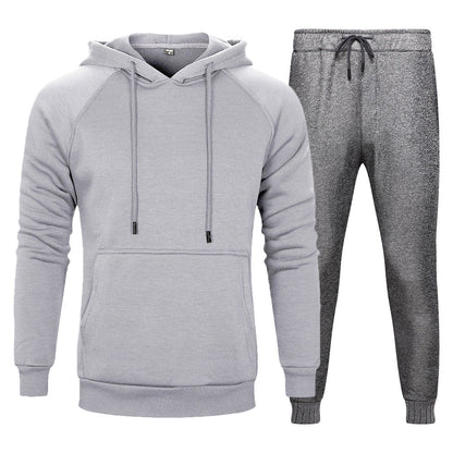 Tuta sportiva grigia da uomo, composta da felpa con cappuccio e pantaloni, ideale per allenamento e tempo libero. Abbigliamento casual e confortevole.