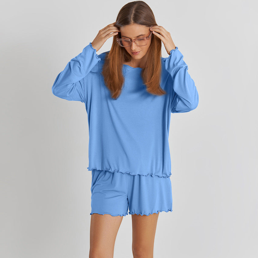 Donna con occhiali indossa pigiama blu a maniche lunghe e pantaloncini coordinati. Moda comoda, abbigliamento da casa, stile casual.